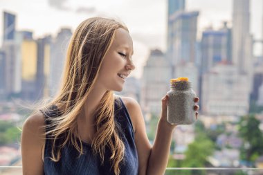 Genç kadın büyük şehir manzaralı onu balkonda Chia puding yemek.