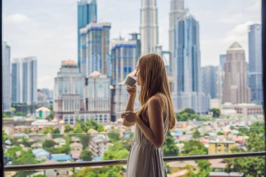 Genç kadın içecekler kahve sabah büyük şehir ve gökdelenler manzaralı balkon.