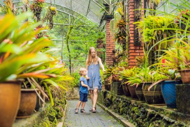Anne ve oğlu tropikal parkta yürüyüş.