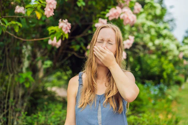 開花ツリーの背景に公園で若い女性のくしゃみ アレルギー花粉コンセプト — ストック写真