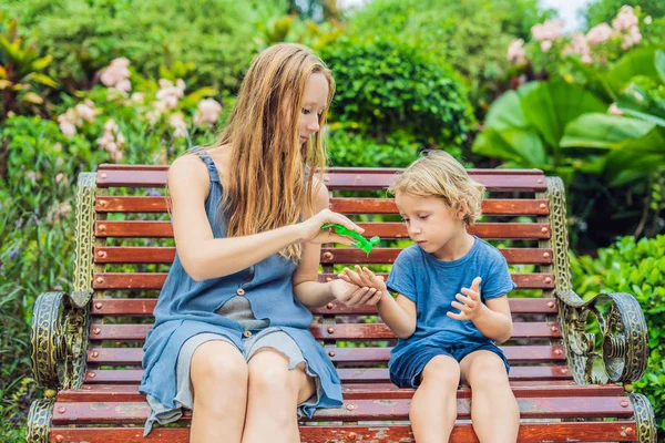 Anne ve oğlu yıkama el kullanarak bir aperatif önce parkta jel dezenfekte