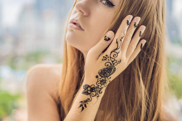 Portrait of a young Indian woman in casual style with mehendi against the background of a big city. Malaysia