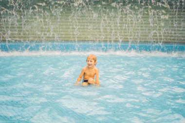 Küçük çocuk yüzme havuzunda eğleniyor.