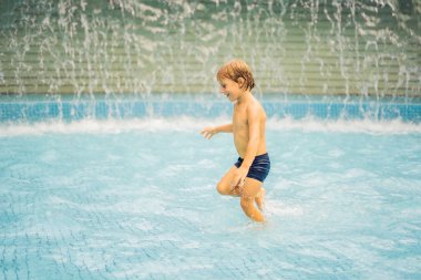 Küçük çocuk yüzme havuzunda eğleniyor.