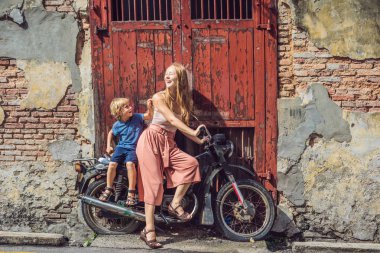 Anne ve oğlu eski bir motosiklet üzerinde. Penang, Malezya.