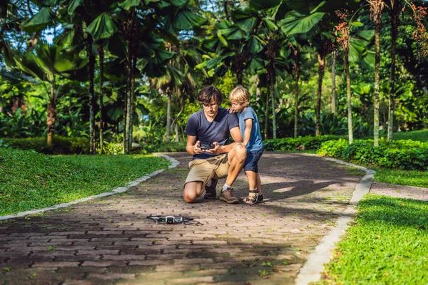 お父さんと息子のドローン 男と少年飛行ドローン父無人機 Quadrocopter 遊んで時間を一緒に過ごす 幸せな少年晴れた秋の庭で遊んで遊んで — ストック写真