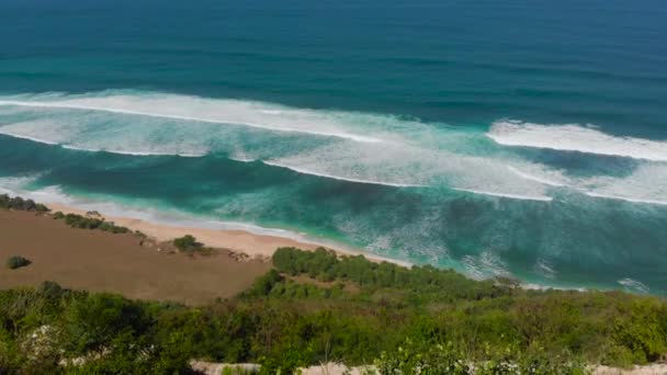 Foto aérea de una joven mujer y su hijo visitando una remota playa - nyang nyang- en la isla de Bali. Parado sobre una roca mirando un océano abierto frente a ellos . — Vídeos de Stock