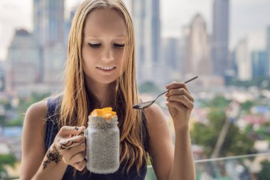 Genç kadın büyük şehir manzaralı onu balkonda Chia puding yemek.