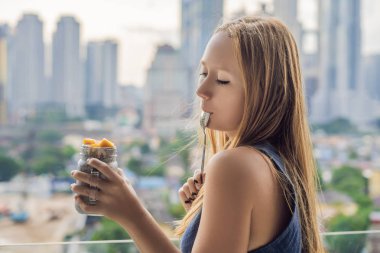 Genç kadın büyük şehir manzaralı onu balkonda Chia puding yemek.