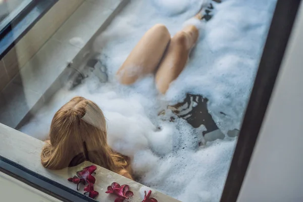 Young Woman Sits Bath Foam Frangipani Flowers Background Panoramic Window — Stock Photo, Image