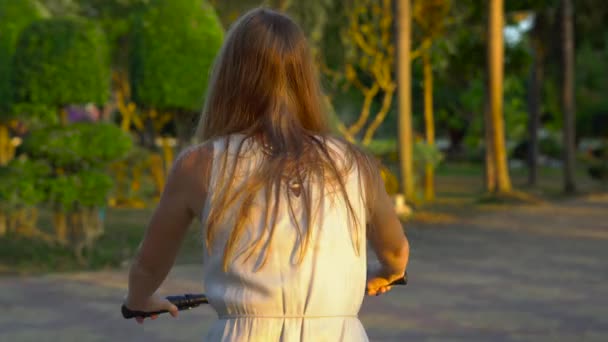 Steadycam shot of a young woman riding a bicycle in a tropical park — Stock Video