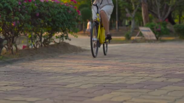 Steadycam shot d'une jeune femme en vélo dans un parc tropical — Video