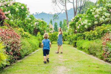 Anne ve oğlu çiçek açan bahçede koşturup. Mutlu aile yaşam tarzı kavramı.