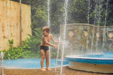 Mutlu çocuk çocuk havuzunda su çeşme ile oynamak