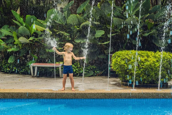 Mutlu çocuk çocuk havuzunda su çeşme ile oynamak