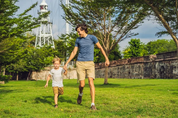 Dad and son on background of Fort Cornwallis in Georgetown, Penang, is a star fort built by the British East India Company in the late 18th century, it is the largest standing fort in Malaysia. Traveling with children concept.