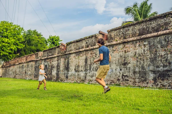 Dad and son on background of Fort Cornwallis in Georgetown, Penang, is a star fort built by the British East India Company in the late 18th century, it is the largest standing fort in Malaysia. Traveling with children concept.
