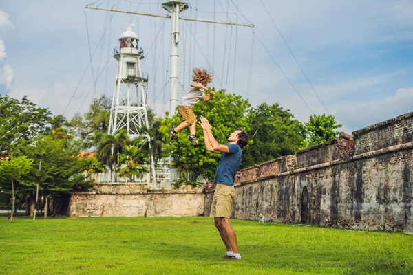 Dad and son on background of Fort Cornwallis in Georgetown, Penang, is a star fort built by the British East India Company in the late 18th century, it is the largest standing fort in Malaysia. Traveling with children concept.