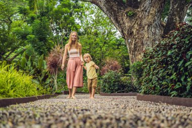 Anne ve oğlu yürümek üstünde A dokulu Arnavut kaldırımı kaplama, refleksoloji. Kaldırımda ayak refleksoloji için çakıl taşları.
