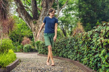 Refleksoloji bir dokulu Arnavut kaldırımı kaldırımda yürüyen adam. Kaldırımda ayak refleksoloji için çakıl taşları.