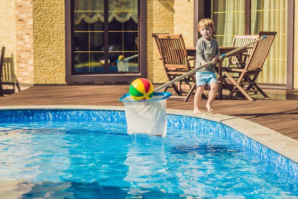 Yürümeye başlayan çocuk havuzunu temizliyor ve topu havuzdan çeker. Havuz temizleyicisi kavramı.