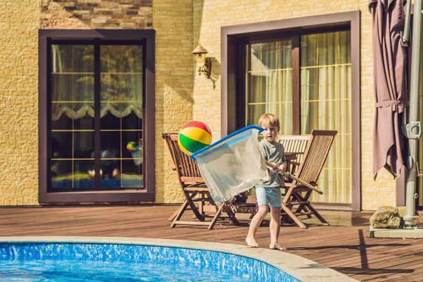 Yürümeye başlayan çocuk havuzunu temizliyor ve topu havuzdan çeker. Havuz temizleyicisi kavramı.
