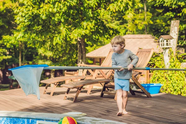 Toddler boy cleans the pool and pulls the ball out of the pool. Pool Cleaner Concept.