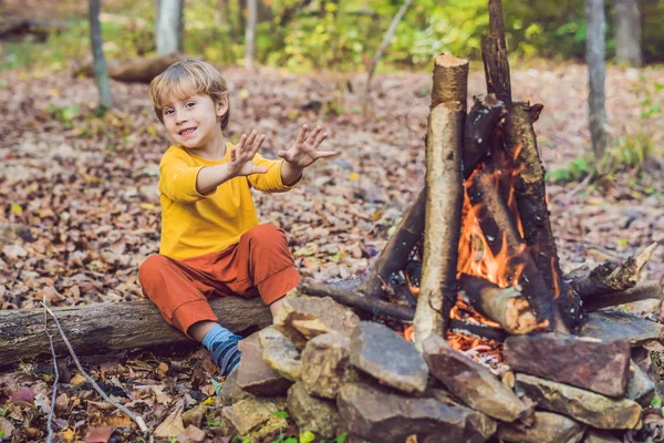 Çocuk oğlan kamp ateşi gündüz oturuyor
