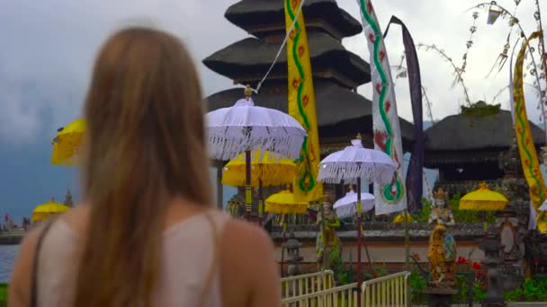 Slowmption schot van een jonge vrouw lopen en fotograferen op een mobiele telefoon de Pura Ulun Danu Tempel op de lake Bratan in Bali, Indonesië — Stockvideo