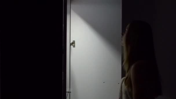 Ung kvinna på natten öppnar garderob och välja klänning till på — Stockvideo