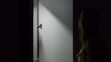 Gece genç kadın bir dolap açar ve üzerinde elbise için seçin