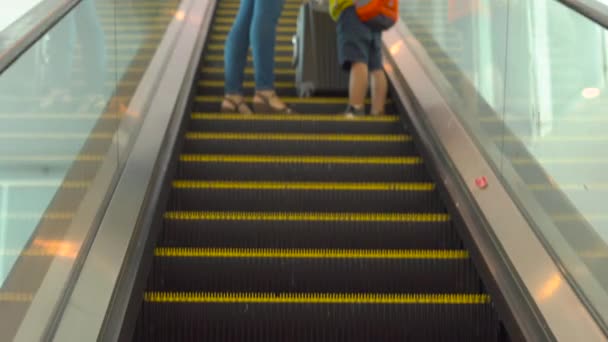 Genç bir kadın ve küçük oğlu bir havaalanında bir yürüyen merdiven kullanarak gidiş Steadicam atış — Stok video
