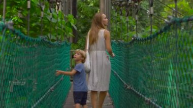 Genç bir kadın ve oğlu asılı asma köprü Kuala Lumpur City Eko Park'ta yürüyüş Steadicam atış