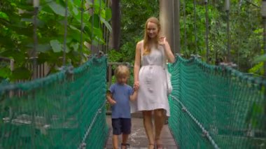 Genç bir kadın ve oğlu asılı asma köprü Kuala Lumpur City Eko Park'ta yürüyüş Steadicam atış