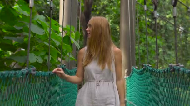 Steadicam shot of a young woman walking on the hanging suspension bridge in the Eco Park in the Kuala Lumpur city — Stock Video