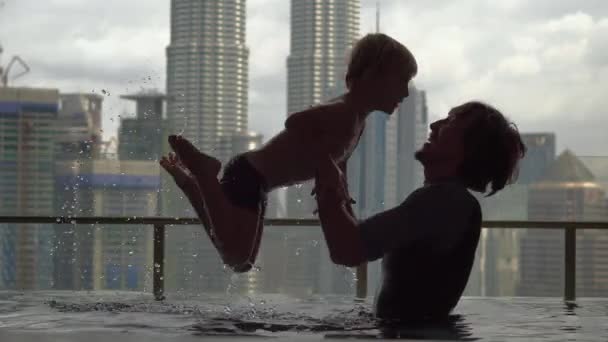 Kuala Lumpur, Malaysia - 12. Mai 2018: Vater und Sohn amüsieren sich im Pool auf dem Dach mit Blick auf Wolkenkratzer — Stockvideo