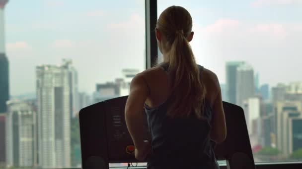 Jonge vrouw in een sportschool op de top van een wolkenkrabber-training op een atletiekbaan met uitzicht op een hele stad — Stockvideo