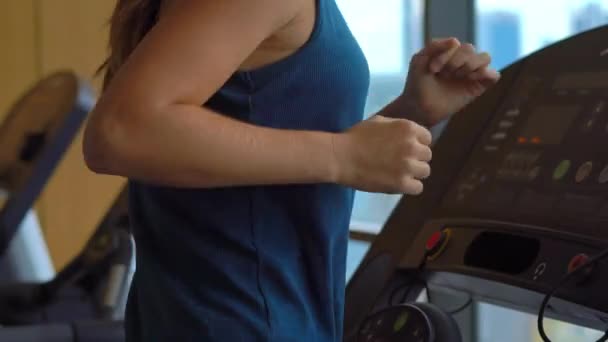 Junge Frau in einem Fitnessstudio auf einem Wolkenkratzer beim Training auf einer Laufbahn mit Blick auf eine ganze Stadt — Stockvideo