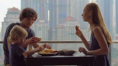 Genç aile bir kahvaltı, Bütün şehir şehir manzaralı bir gökdelen onların balkonda yemek
