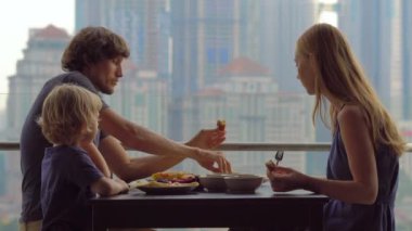 Genç aile bir kahvaltı, Bütün şehir şehir manzaralı bir gökdelen onların balkonda yemek