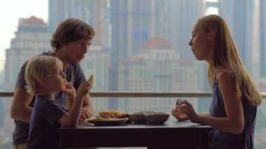 Genç aile bir kahvaltı, Bütün şehir şehir manzaralı bir gökdelen onların balkonda yemek