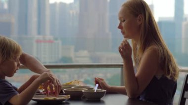 Genç aile bir kahvaltı, Bütün şehir şehir manzaralı bir gökdelen onların balkonda yemek