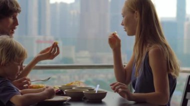 Genç aile bir kahvaltı, Bütün şehir şehir manzaralı bir gökdelen onların balkonda yemek