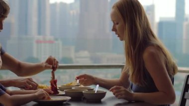 Genç aile bir kahvaltı, Bütün şehir şehir manzaralı bir gökdelen onların balkonda yemek