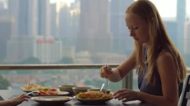 Genç aile bir kahvaltı, Bütün şehir şehir manzaralı bir gökdelen onların balkonda yemek