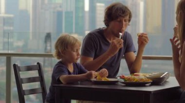Genç aile bir kahvaltı, Bütün şehir şehir manzaralı bir gökdelen onların balkonda yemek