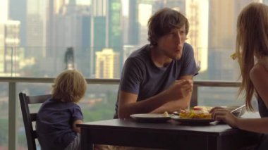 Genç aile bir kahvaltı, Bütün şehir şehir manzaralı bir gökdelen onların balkonda yemek