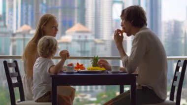 Genç aile bir kahvaltı, Bütün şehir şehir manzaralı bir gökdelen onların balkonda yemek