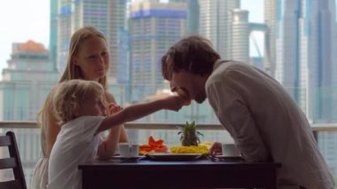 Genç aile bir kahvaltı, Bütün şehir şehir manzaralı bir gökdelen onların balkonda yemek
