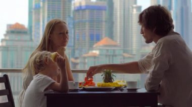 Genç aile bir kahvaltı, Bütün şehir şehir manzaralı bir gökdelen onların balkonda yemek